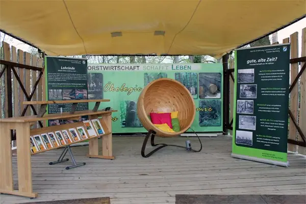 Überdachter Ausstellungsstand der Landesgartenschau mit einer Holzkugel zwischen Infotafeln